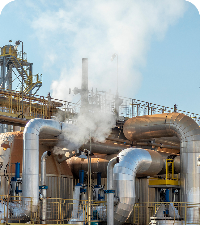 GettyImages-1146054915 Industrial pipes emitting steam under clear sky.